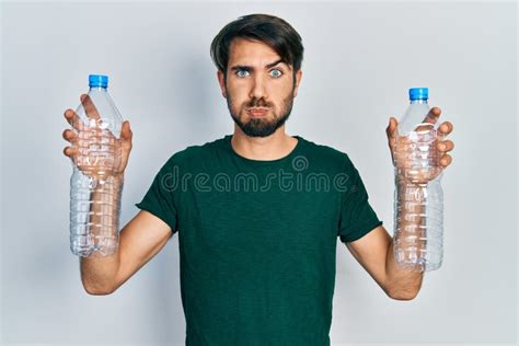 Young Hispanic Man Holding Recycling Plastic Bottles Puffing Cheeks