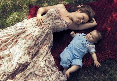 A Mother And Baby Laying On A Blanket In The Grass