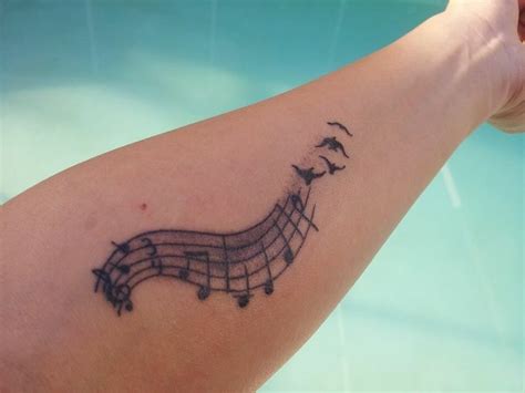 A Tattoo With Musical Notes On It S Arm And Birds Flying Around The Band