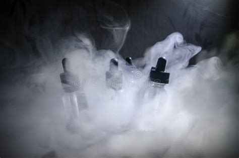 Vape Concept Smoke Clouds And Vape Liquid Bottles On Dark Background