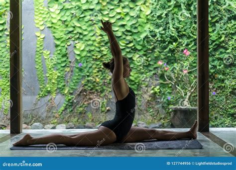 Side View Of Beautiful Young Woman Practicing Yoga In Front Splits Pose