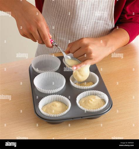 Woman Spooning Cake Batter Into Cupcake Cases Stock Photo Alamy