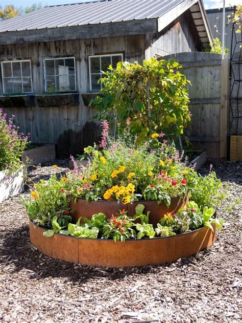 A Garden Filled With Lots Of Flowers Next To A Wooden Fence And Building In The Background