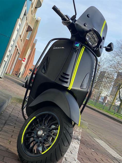 A Black And Yellow Scooter Parked On The Sidewalk