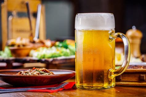 Un Vidrio De Cerveza Ligera En El Fondo De Una Tabla Con Bocados Foto