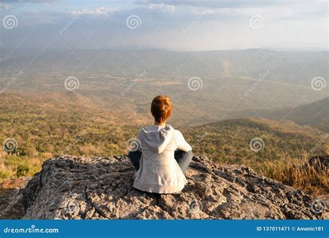 A Woman Sitting On Rocky Mountain Looking Out At Scenic Natural View