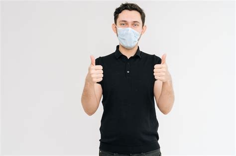 Homem bonito caucasiano máscara médica em camiseta preta mostrando