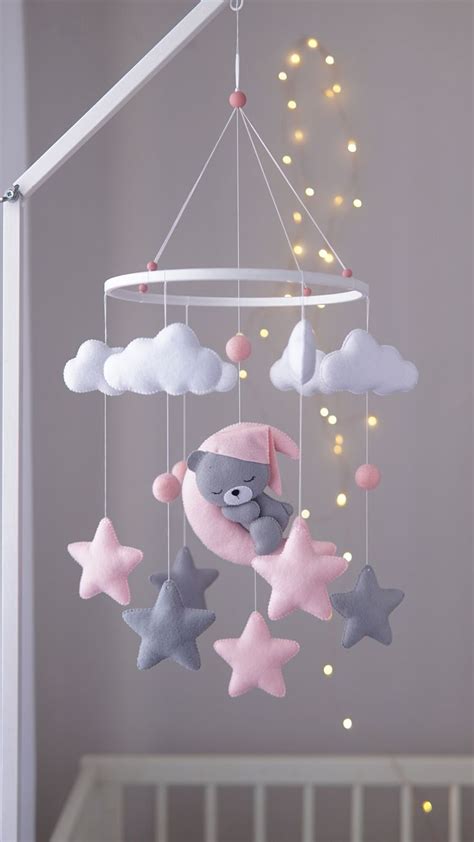 A Baby Crib Mobile With Pink Grey And White Stars Hanging From The Ceiling