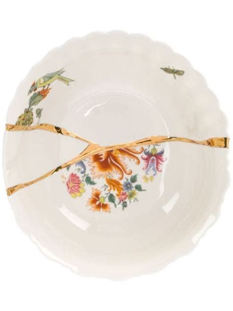 Two Golden Forks On A White Plate With Flowers And Leaves Painted On