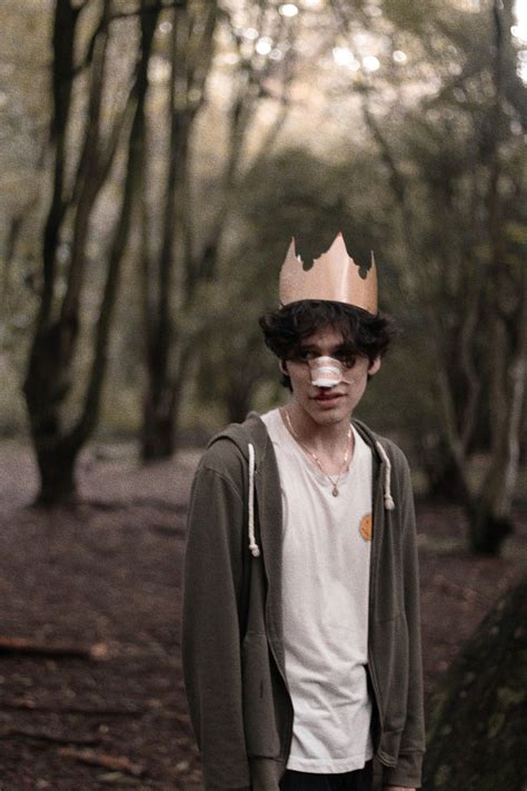 A Man With A Crown On His Head Standing In The Middle Of A Wooded Area