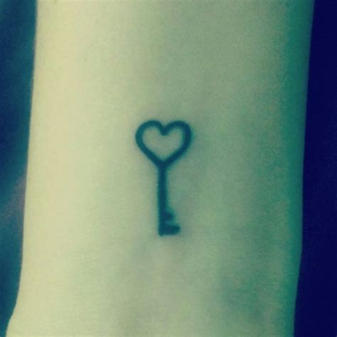 A Small Key Tattoo On The Wrist With A Heart Shaped Key In Its Center