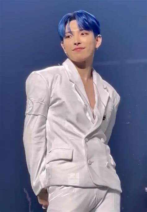 A Male In A White Suit And Blue Hair Posing For The Camera With His