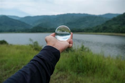 Premium Photo Cropped Hand Of Person Holding Crystal Ball By Lake