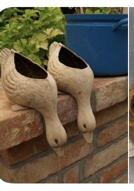 Two Wooden Shoes Sitting On Top Of A Brick Wall Next To A Potted Plant