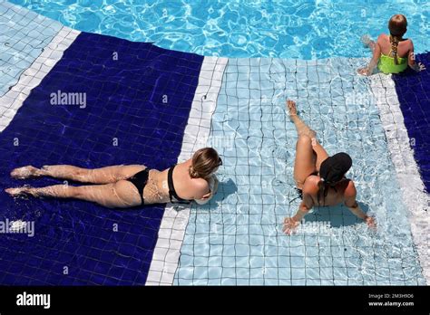 Dos mujeres jóvenes con bikini negro y niña bronceándose en el agua