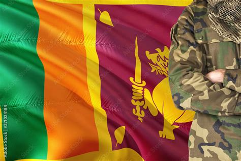 Crossed arms Sri Lankan soldier with national waving flag on background ...