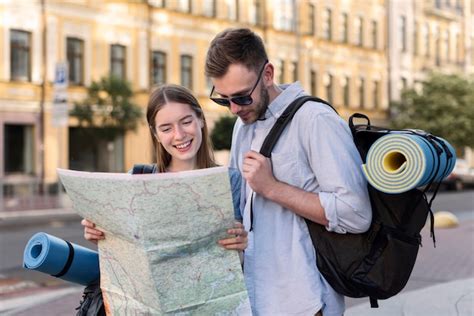 Casal de turista segurando o mapa enquanto carregava mochilas Foto Grátis