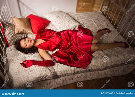 Sensual Brunette In A Red Dress Lying On The Bed Stock Photos Image