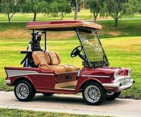 A Red Golf Cart Parked On The Side Of A Road Next To A Green Field