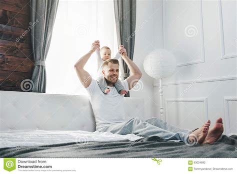 Happy Father With His Son Playing At Home On The Bed Stock Photo