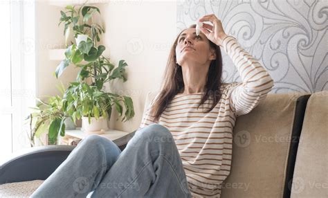 Head shot young caucasian woman using medical eyes drops suffering from