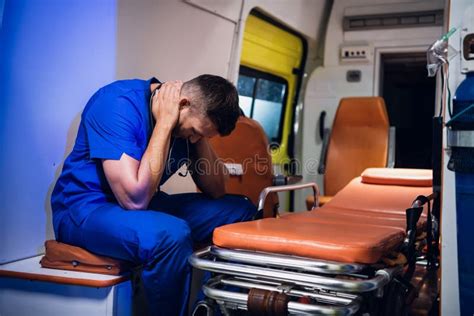 Tired Paramedic In A Blue Uniform Holding His Stethoscope Sitting In