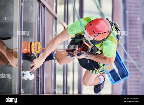 Industrial Mountaineering Worker Washing Glass Windows Of High Rise