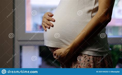 Close Up View Of Standing Pregnant Woman Gently Stroke Her Belly Stock