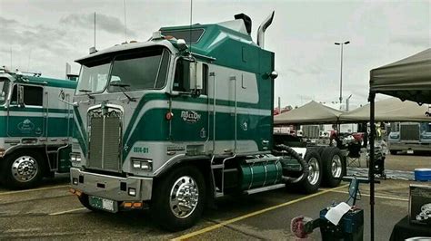 Two Green Semi Trucks Parked Next To Each Other In A Parking Lot With