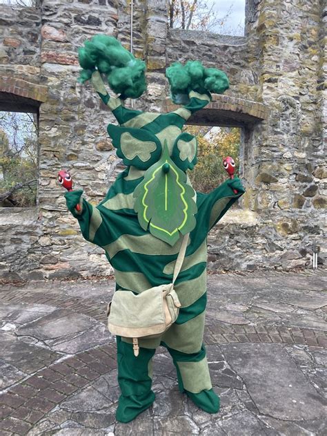 a person in a costume standing on a stone walkway with their arms up ...