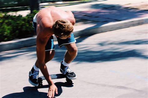 A Man Riding A Skateboard Down The Side Of A Road