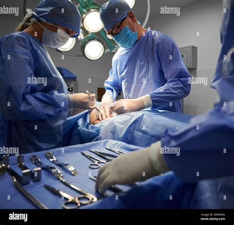 Medical team in surgical suits performing aesthetic surgery in ...