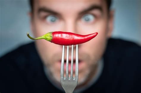 Premium Photo A Man Is Afraid To Eat Hot Peppers Ridiculous Expression Of A Man With Hot