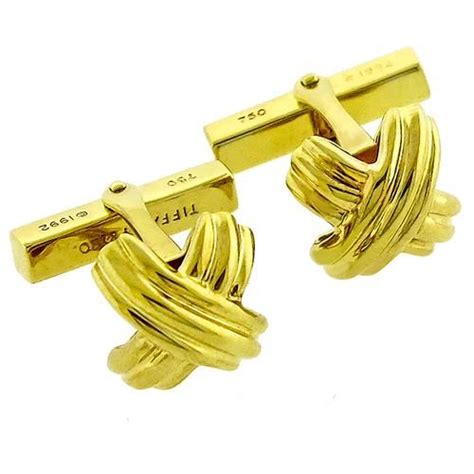 Two Gold Toned Cufflinks With Cross On Each End Set Against A White