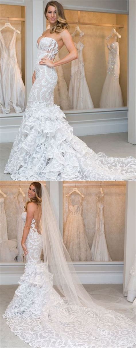 A Woman In A White Wedding Dress Standing Next To A Window With Dresses