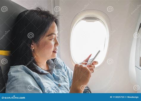 Asian Woman Sitting At Window Seat In Airplane And Turn On Airplane