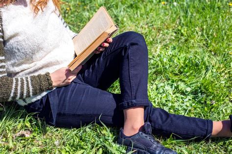 Premium Photo Young Women Sitting On Green Grass And Reading Book