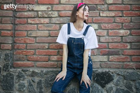 Slim Sexy Brunette Girl Wearing Womans Denim Overall Over Green Tree