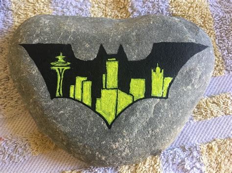 A Painted Rock With The Shape Of A Batman Symbol On It