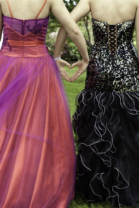 Two Women In Dresses Standing Next To Each Other On The Grass With Their Hands Behind Their Backs