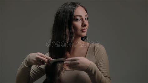 Uma Jovem Morena Charmosa Penteia Seu Cabelo Longo E Ondulado Em Um