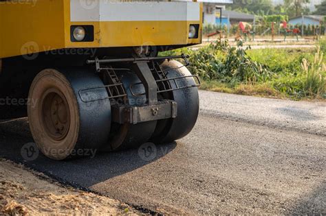 Yellow Steamroller Or Soil Compactor Working On Asphalt Road At