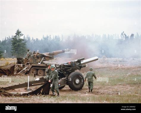 US Army artillery crews conduct a firing exercise with an M114 155 mm howitzer, bottom, and an ...