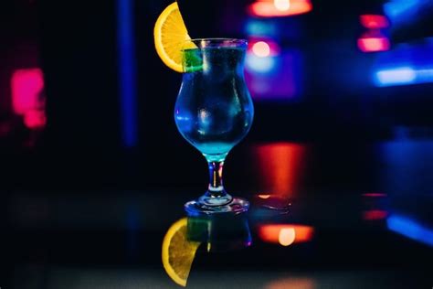 Copa de cóctel de alcohol azul martini con una rodaja de naranja en el