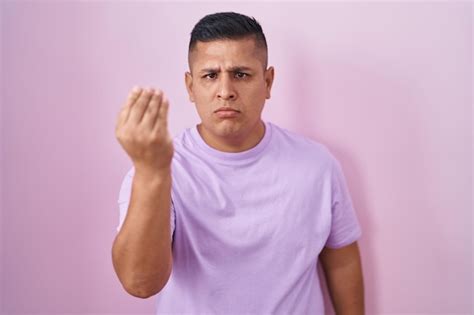 Joven Hispano Parado Sobre Un Fondo Rosa Haciendo Un Gesto Italiano Con