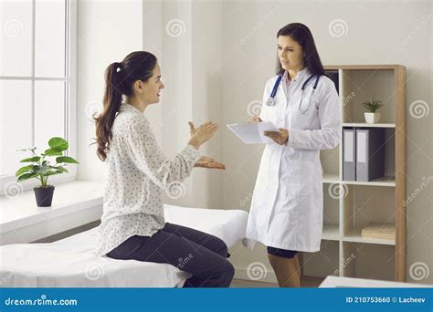 Woman Sitting On Examination Bed And Talking To Doctor During Medical