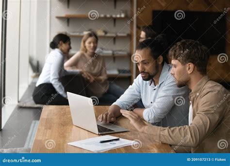 Two Diverse Male Employees Working On Project Together Using Laptop