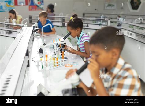 Multiracial Elementary Students Using Microscope During Science