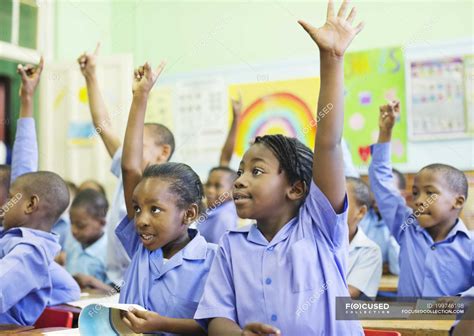 African American Students Raising Hands In Class Looking Away