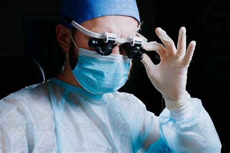 Surgeon Wearing Binocular Magnifying Glasses Operates On A Patient In A